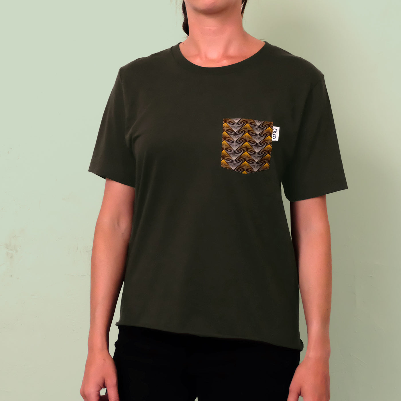 Woman wearing dark green t-shirt with gold and gray chest pocket