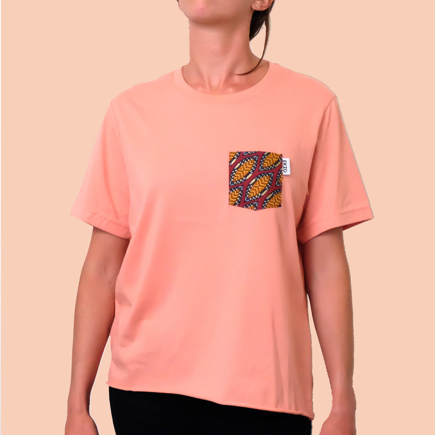 Woman wearing salmon colored t-shirt with African wax fabric chest pocket