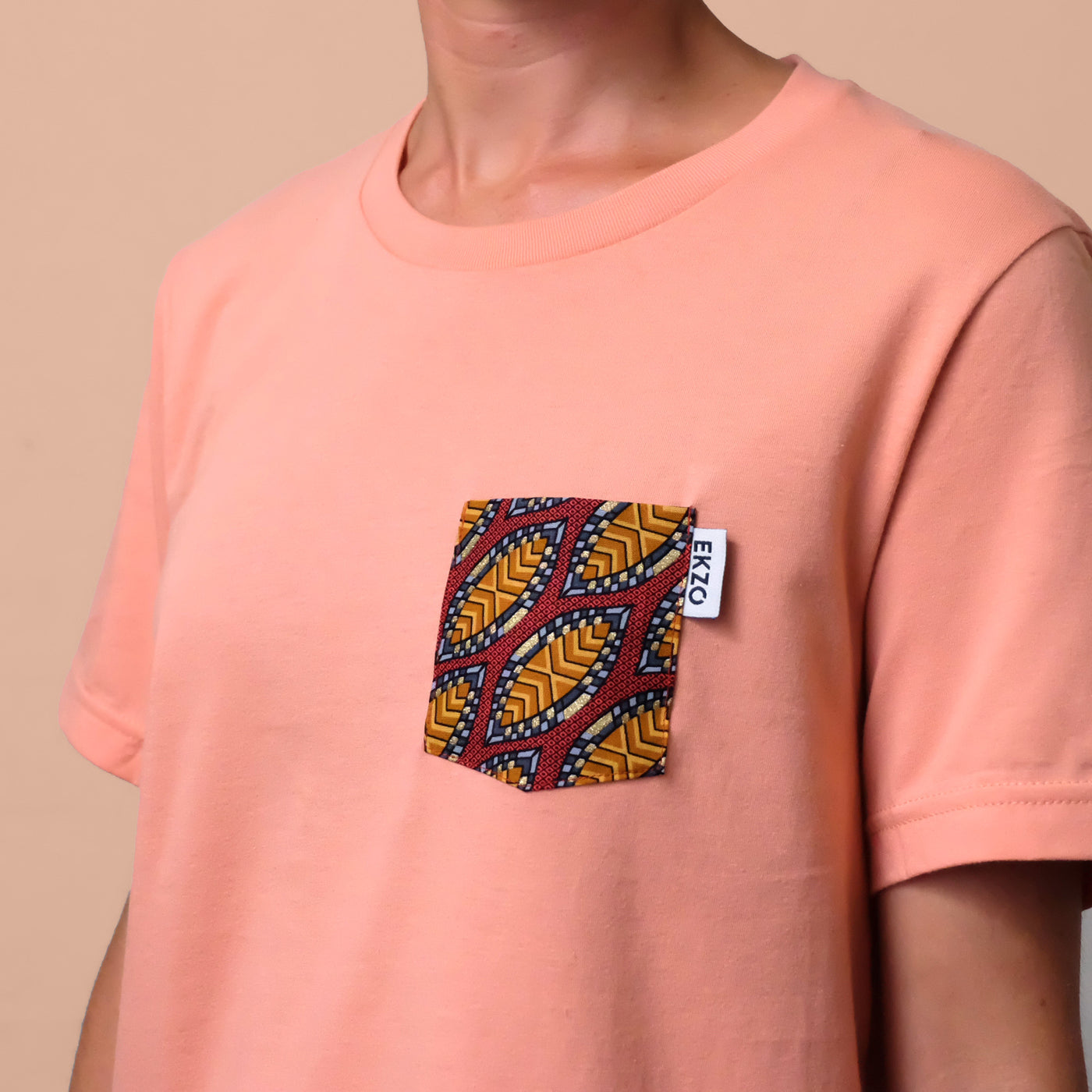 Close-up of wax fabric chest pocket on a salmon colored t-shirt