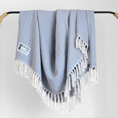 Blue and white blanket with white tassels hanging on rack