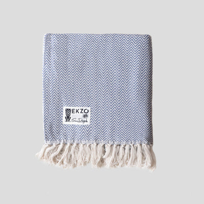 Blue and white woven blanket with white tassels folded in square 