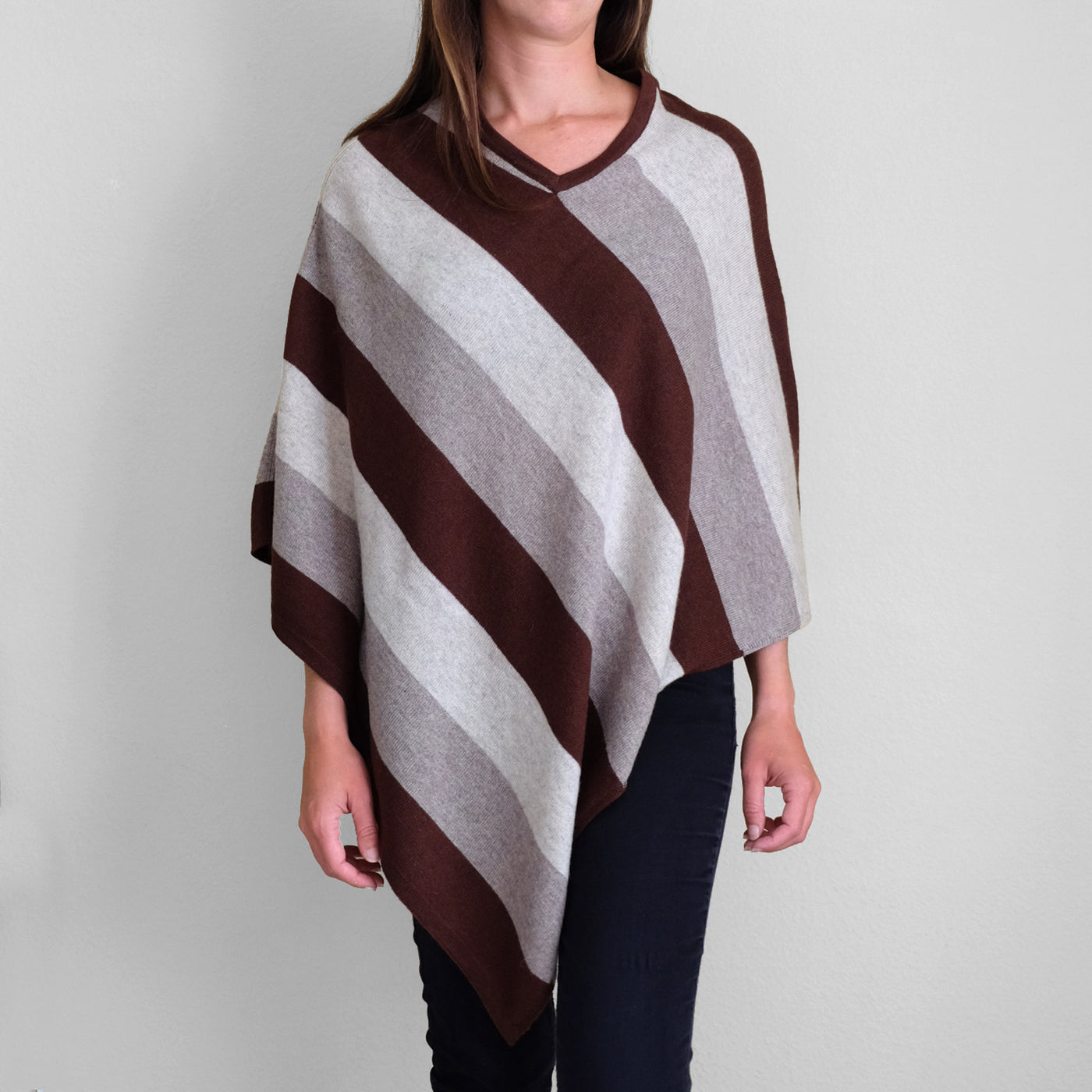 Woman wearing white gray and brown striped poncho